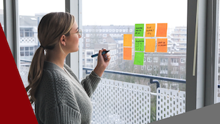 A woman writing on post-it notes on a window